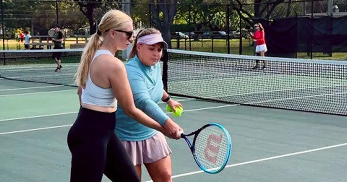 A coach working with a player on the forehand