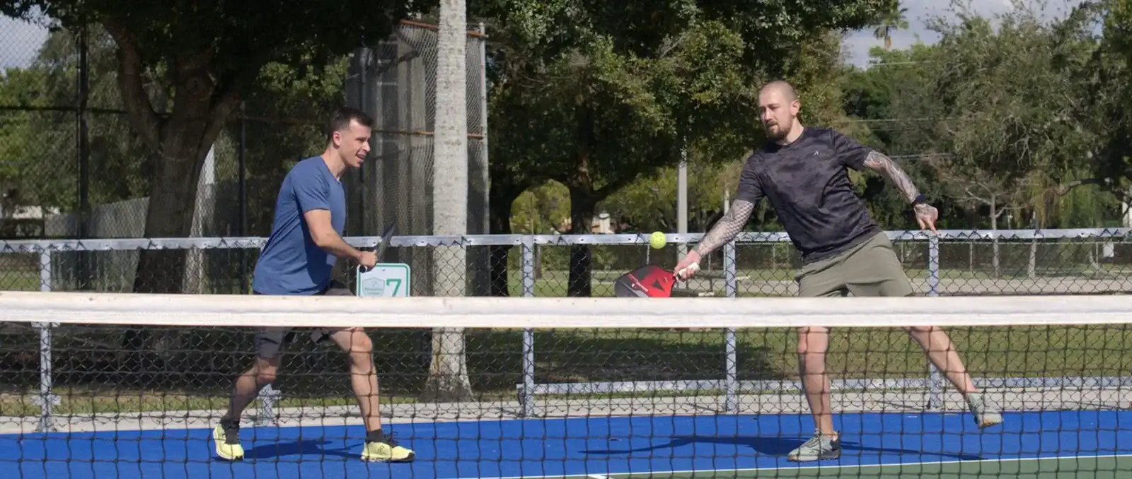 Two adults playing pickleball at the net
