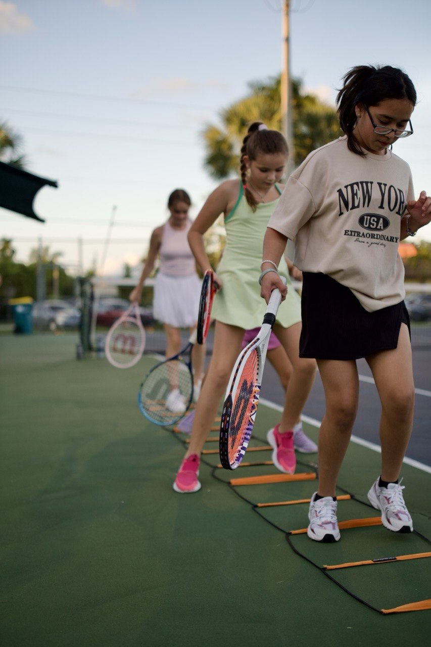 Girls doing an agility-ladder footwork drill at an evening class