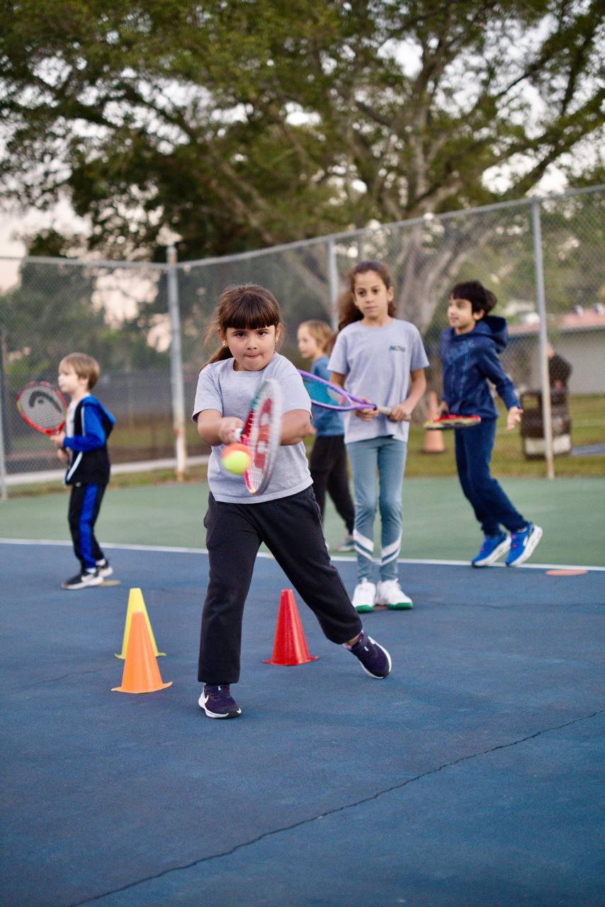 Child hitting a forehand between cones during a kids class