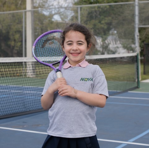 Smiling girl in a NOVA T-shirt with a purple racket on court