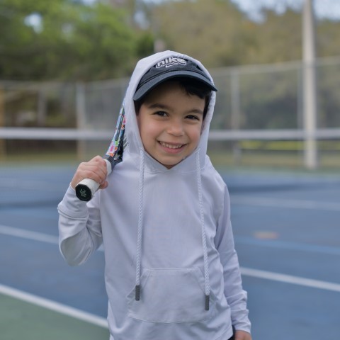 Boy in a cap and hoodie with his racket over his shoulder