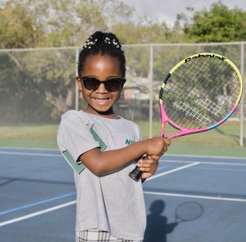 Girl in sunglasses holding her racket on court
