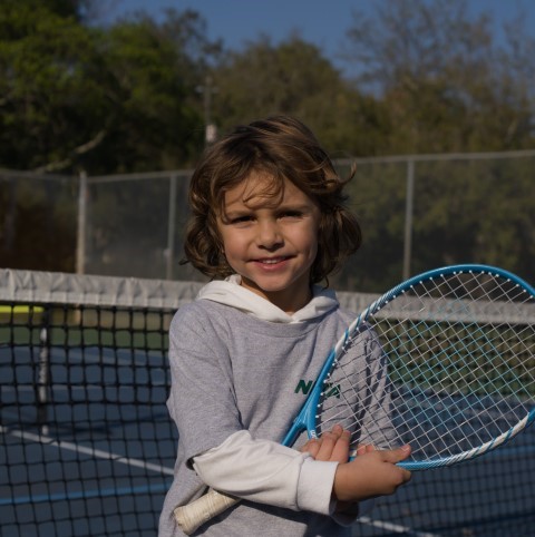Young player with a blue racket at the net