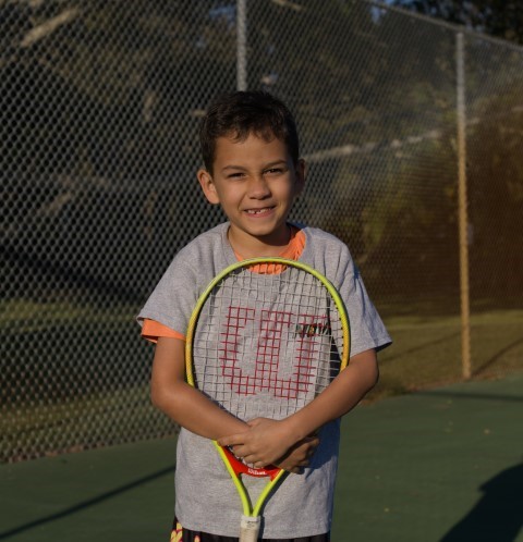 Boy holding his racket in front of him on court