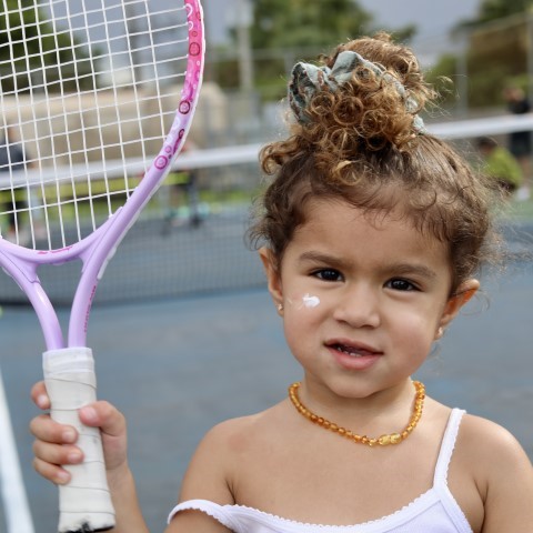 Toddler holding a purple tennis racket
