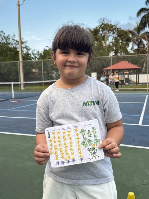 Girl in a NOVA T-shirt showing her progress sticker card